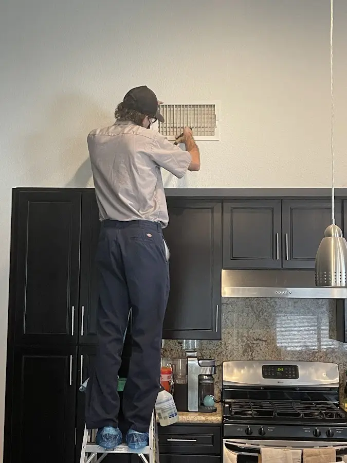Technician inspecting an air vent during HVAC service in Greenville